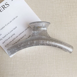 Detail der silbernen Glitzer-Oberfläche und des durchscheinenden Harzes der Haarklammer