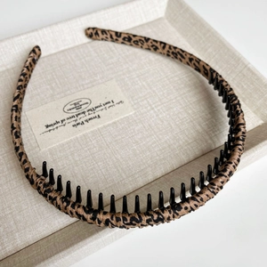 Detail of leopard print headband with non-slip inner teeth on a beige display tray