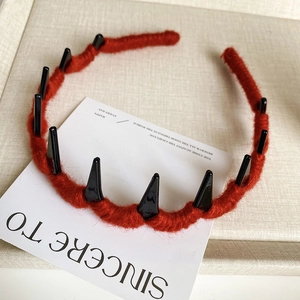Detail of red yarn-wrapped headband with black demon spikes and anti-slip comb teeth