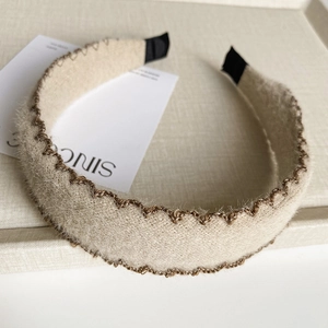 Détail du serre-tête tricoté beige avec bordure brodée marron en forme de vagues