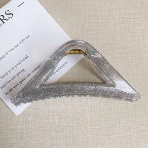 Detail einer großen dreieckigen Haarklammer mit silbernem Glitzer und goldener Feder
