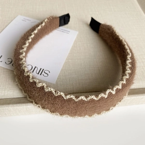 Gros plan du serre-tête en peluche marron avec tricot ondulé et embouts noirs
