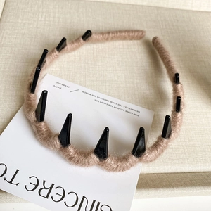 Detail of wave-shaped brown knit headband with non-slip teeth on a soft fabric surface