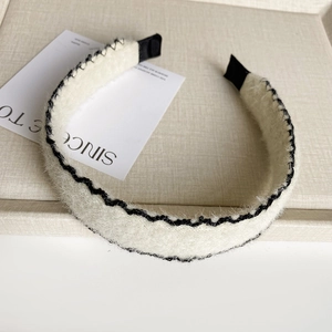 Détail du serre-tête en laine blanche avec broderie ondulée noire et texture premium