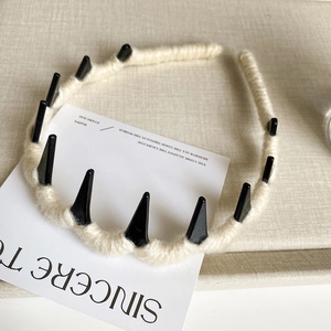 Detail of cream wool-wrapped headband with black punk spikes and anti-slip toothed design