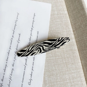 Close-up of zebra pattern hair clip on a neutral fabric background for hair styling