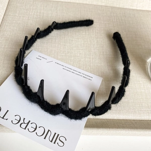 Close-up of black yarn-wrapped wavy headband with polished anti-slip plastic teeth