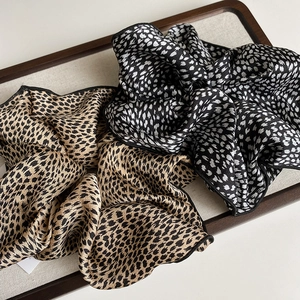 Elegant satin leopard print scrunchies in brown and black-white tones for hair styling