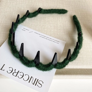 Detail of dark green plush headband featuring unique black plastic triangular teeth design