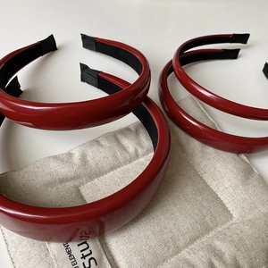 Macro shot of glossy red faux leather headbands showing the black fabric lining and texture