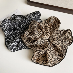 Detail of satin leopard and polka dot scrunchies with black edges on beige background