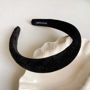 Detailed macro view of black velvet padded headband with Handmade label on white tray