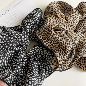 Close-up of leopard print scrunchies in black, white and brown leopard pattern
