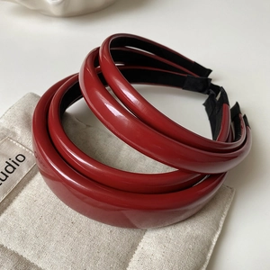 Detail of dark red glossy leather headbands with black lining on a beige fabric bag