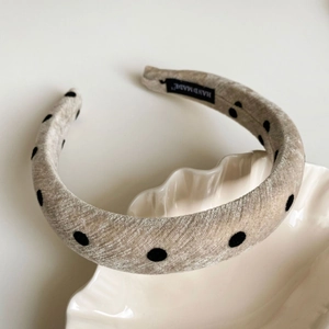 Detail of handmade beige polka dot headband displayed on a white shell ceramic plate