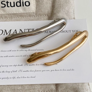 Detail of minimalist metallic hair clips in gold and silver finish on textured fabric