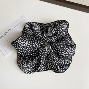 Detail of a large black scrunchie with white dots and high-quality silk texture