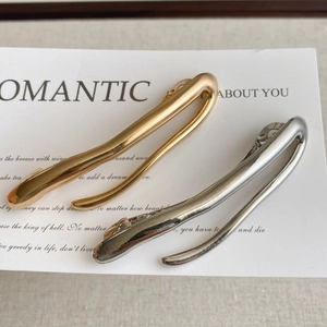 Minimalist metallic hair clips in gold and silver finish on a clean aesthetic background