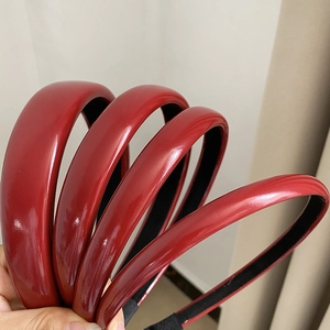 Close-up of set of five red glossy faux leather headbands in various widths for women