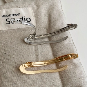 Macro detail of curved metal hair clip showing the CLIP THREE engraving and inner grip texture