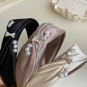 Detail of satin headbands with pearl and rhinestone butterfly on elegant fabric