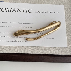 Detailed close-up of a minimalist irregular gold metal hair clip on a display card