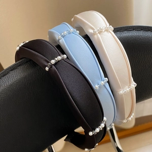 Detailed view of padded satin headbands with white pearls and transparent beads