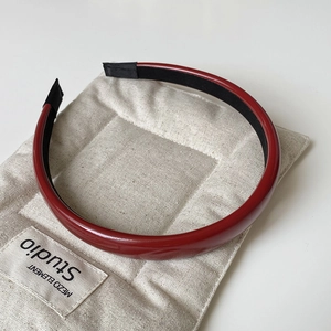 Detailed close-up of dark red glossy leather headband with black anti-slip lining