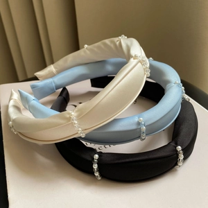 Three elegant padded headbands with pearls and crystals in white, blue, and black colors