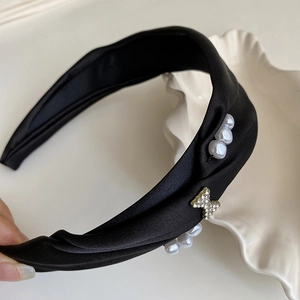 Detailed macro view of black satin headband with white faux pearls and a rhinestone butterfly