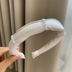 Detailed view of elegant padded cream satin headband with pearl and bead embellishments
