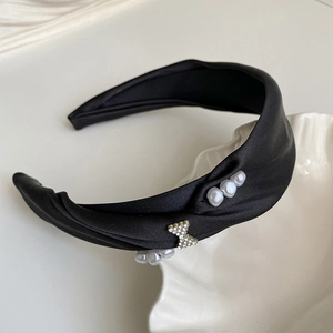 Detail of black satin headband with pearls and diamond butterfly knot on a shell tray
