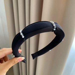 Detail of black velvet headband with white faux pearls and crystal beads on woven texture