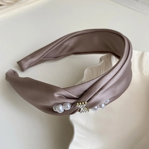 Detailed view of the light brown satin headband with elegant pearls and rhinestone bear