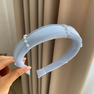 Close-up of light blue satin headband with handcrafted white pearls and crystal beads
