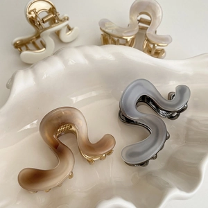 Close-up of elegant acetate shark hair clips in four colors on a white shell tray