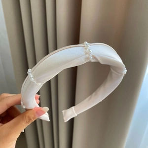 Detailed view of elegant white padded satin headband decorated with transparent crystal beads