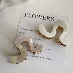 Detail of wavy acetate hair claws with iridescent pearl finish and metal spring clips