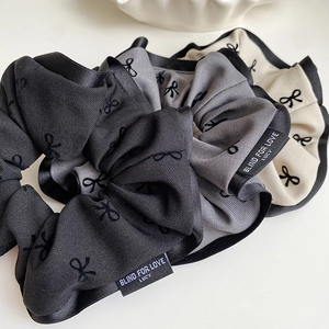 Three-piece set of elegant bow scrunchies in black, grey, and cream with satin edges