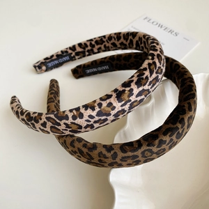 Detailed close-up of leopard print velvet sponge headbands with a handmade woven label