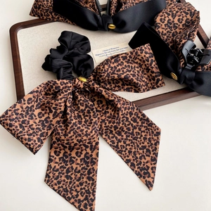 Ensemble chouchou à nœud léopard et pince à cheveux noire sur un plateau en bois rétro