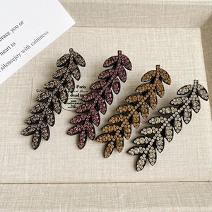 Sparkling leaf hair clip set with four colored rhinestones on a vintage beige background