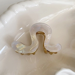 Detailed view of white pearlescent wave hair claw clip with golden metal base