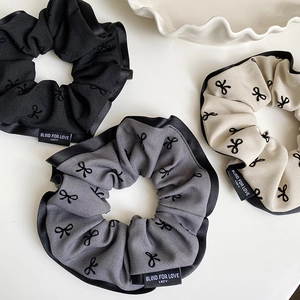 Close-up of bow pattern fabric scrunchies in black, gray, and beige colors