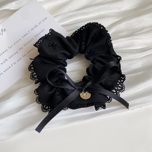 Detailed shot of black lace scrunchie with ribbon bow and golden metal pendant