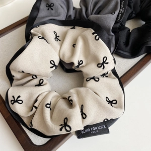 Detail of fabric scrunchies with bow patterns and Blind For Love woven labels