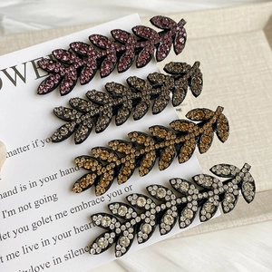 Close-up of sparkling rhinestone leaf hair clips in purple, brown, gold and silver finishes