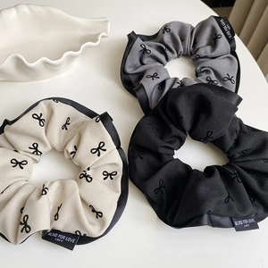 Three-piece set of ribbon bow scrunchies in cream, grey and black with detailed embroidery