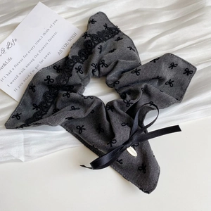Detail of grey scrunchie with bow print, black lace trim and golden logo plaque
