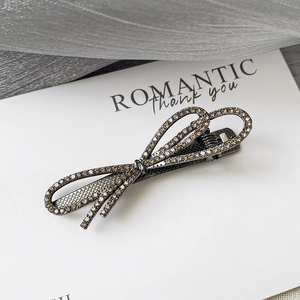 Détail d'une pince à cheveux avec nœud en métal gunmetal et strass champagne brillants
